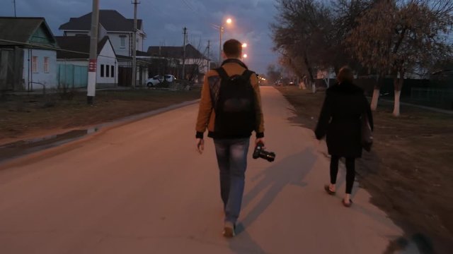 Handheld shot following a man and a woman walking down a street in Oral, Kazakhstan at night time, Tourists sight spotting.