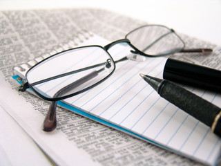 glasses, pen, and notebook on paper