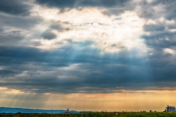 Naklejka premium View from the highway to Kovilj city and the mountain Fruska Gora from Serbia. Black clouds over the urban city with sun rays penetrating through.