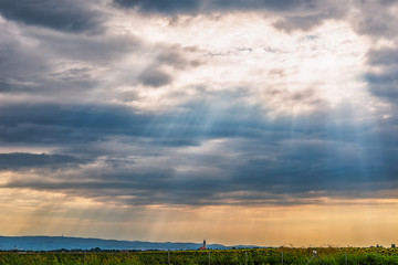 Naklejka premium View from the highway to Kovilj city and the mountain Fruska Gora from Serbia. Black clouds over the urban city with sun rays penetrating through.