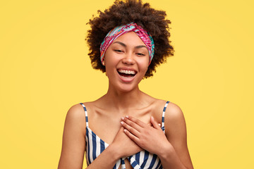 Positive dark skinned young woman with pleased expression, feels satisfied to hear compliment or...
