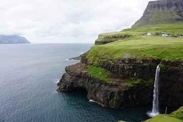 Gasadalur waterfall into the sea with clouds on the Faroe Islands in summer