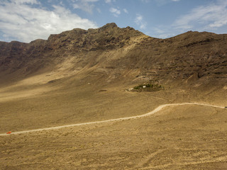 Vista aerea di una strada che costeggia il risco di Famara, Lanzarote, isole Canarie, Spagna. Risco de Famara, montagne a picco sull’Oceano Atlantico 