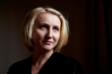 Portrait of a middle-aged woman in the room. Photography in the Studio. Photo shoot in a dark key