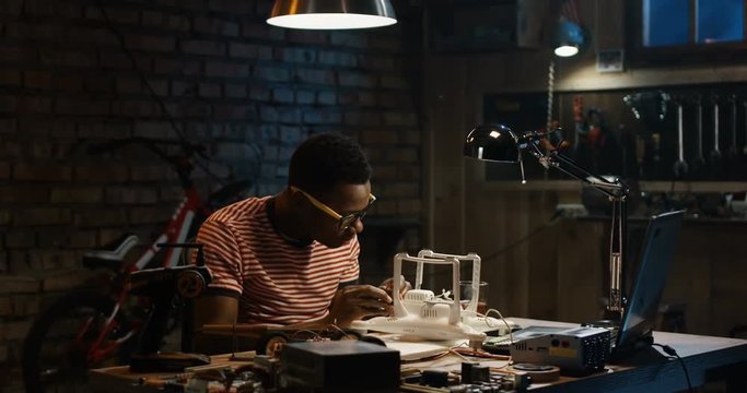 Slow motion shot of a young man repairing a drone in a garage