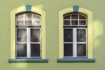 Two windows on  a green wall