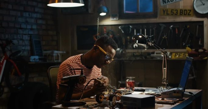 Slow motion shot of a African-American man repairing a mother board in a garage