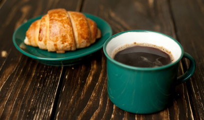mug of coffee, croissant on wooden background