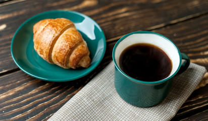 mug of coffee, croissant on wooden background