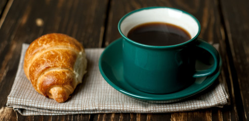 mug of coffee, croissant on wooden background