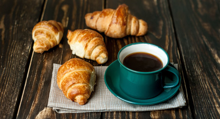mug of coffee, croissants on wooden background