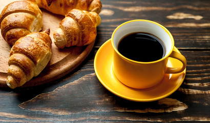 mug of coffee, croissants on wooden background
