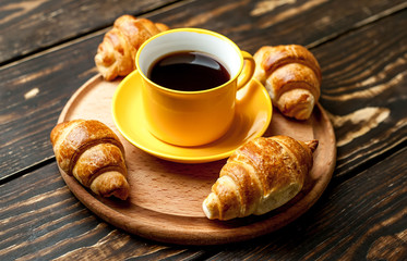 mug of coffee, croissants on wooden background