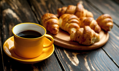 mug of coffee, croissants on wooden background