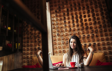 Young pretty caucasian woman in cafe in city centre with tablet laptop