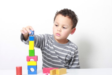 little boy testing his creativity by building towers with toy building blocks