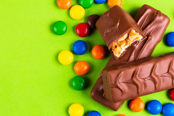 Tasty chocolate bars with toffee and nuts and colorful glazed round candies