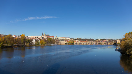 Fototapeta premium Colorful autumn Prague gothic Castle and Charles Bridge with the Lesser Town in the sunny Day, Czech Republic