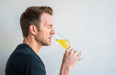 profile of a handsome Caucasian man with his eyes closed savoring a glass of champagne