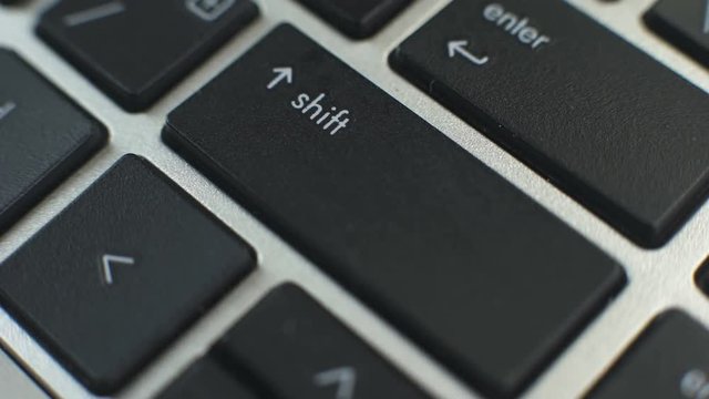 Woman pressing modifier shift button on laptop keyboard to type capital letters