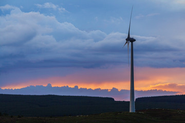 Wind Turbine with sheep grazing Beneath as Sun sets