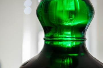 green liquor bottle closeup neck detail on white  neutral background with copy space