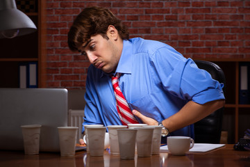 Young employee drinking coffee working at night shift 
