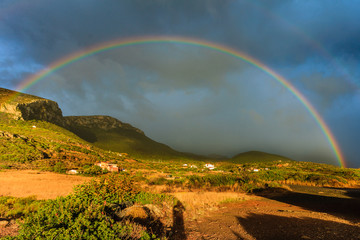 Rainbow on dark cloudy sky in Greece