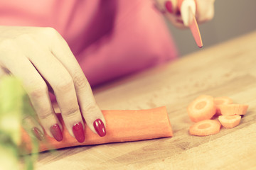 Obraz na płótnie Canvas Woman cutting carrot on kitchen board