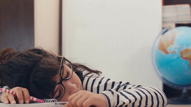 Cute caucasian girl with glasses sleeping over her homework and waking up, 4k