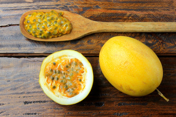 passion fruit pulp on the wooden spoon next to passion fruit on wooden table