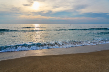  Silhouette of a ship on the sea on a sunset with waves on the beach.