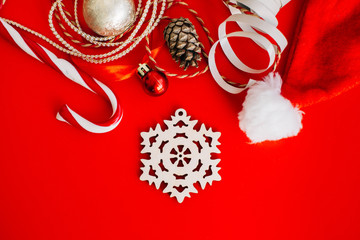 Wooden decoration on the Christmas tree in the form of snowflakes on a red background surrounded by Christmas elements. Place for text.