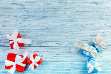 Christmas gifts packed with ribbons on wooden background