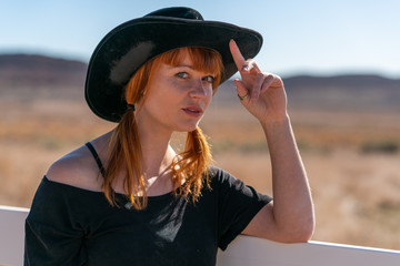Ginger cowgirl with skirt and black top in the desert