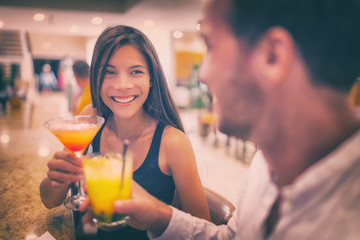 Bar drinking cocktails young couple in love dating talking with drinks at restaurant at night. People at restaurant with alcoholic cocktail beverage.