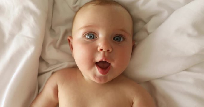 Newborn baby girl laughs lying on her back on the bed