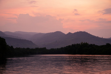 Romantic pink sunset with still lake and distant mountains. Beautiful asian landscape photo. Fresh water river