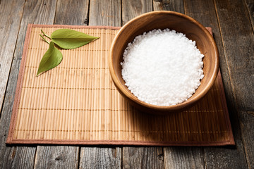 Wooden bowl with salt on natural background