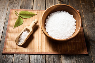 Wooden bowl with salt on natural background