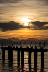 The silhouettes of airport light poles early in the morning at sunrise at Kerkira island, Corfu, Greece. Scenery golden curves of mountain range and clouds in the background