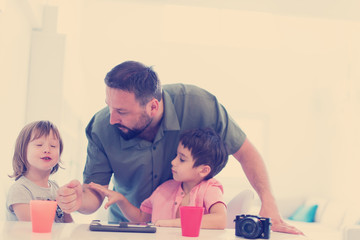 single father at home with two kids playing games on tablet