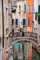 Houses along narrow canal connected by a stone bridge in Venice, Italy
