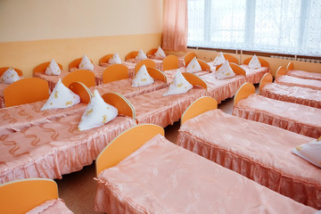 Cots in the kindergarten. Orphanage or boarding school. Beds in a boarding school or in an orphanage - obrazy, fototapety, plakaty