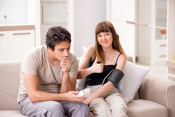 Obraz premium Husband checking wife's blood pressure