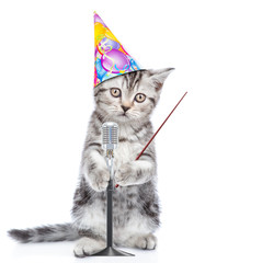 Kitten in birthday hat singing with microphone a karaoke song and pointing stick. isolated on white background