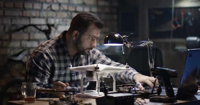 Medium shot of a man repairing a drone in a garage