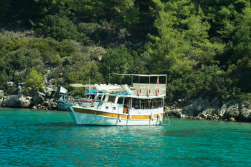 Fototapeta premium Recreation on the boat near the shore of a mountain and forest. beautiful lagoon. ship in the bay. summer vacation