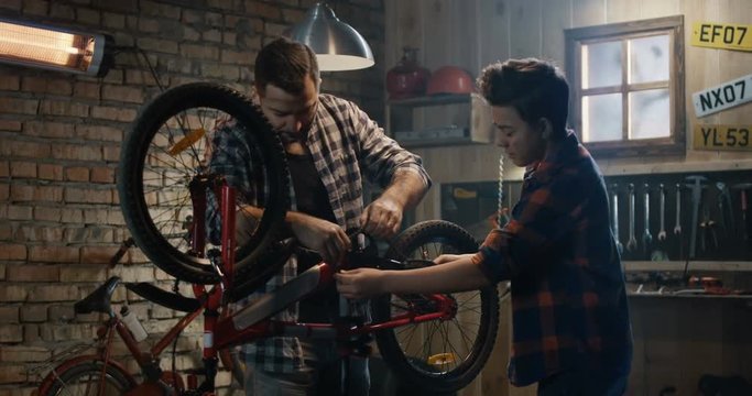 Medium shot of father and son repairing a bicycle in a garage