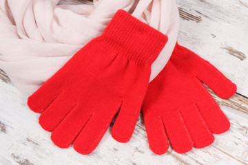 Red womanly gloves with shawl for autumn or winter on old rustic board